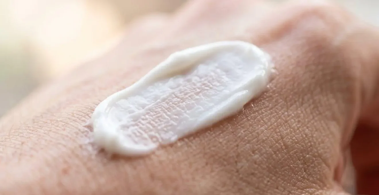 Gros plan macro sur une texture crémeuse blanche appliquée sur la peau avec un flou artistique en arrière-plan